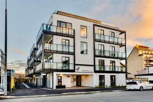 a large white building with a car parked in front of it at Central City Apartment 'The Olive' in Christchurch