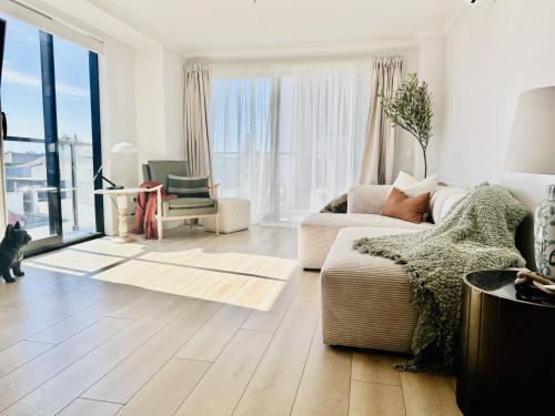 a living room with a couch and a large window at Central City Apartment 'The Olive' in Christchurch