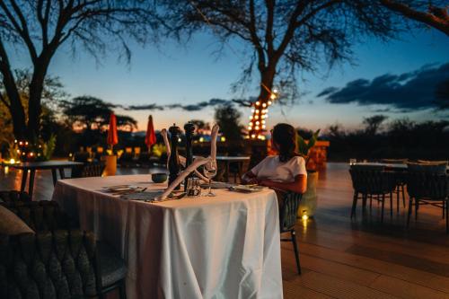 a woman sitting at a table with a table cloth at Elephant lodge in Kwa Kuchinia