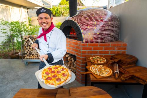 a man holding a pizza in front of an oven at Anantara Vacation Club Mai Khao Phuket in Mai Khao Beach