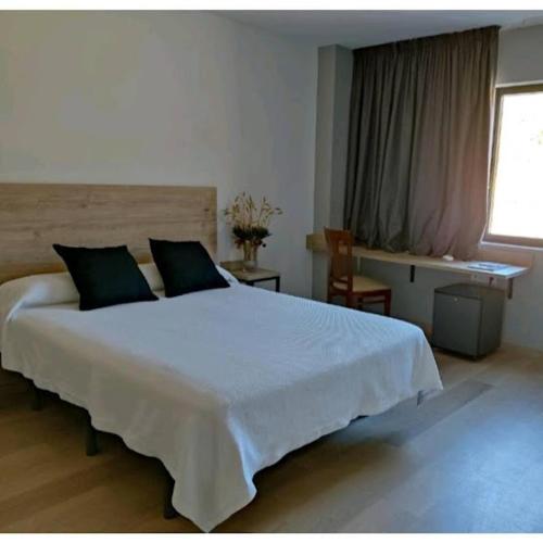 a bedroom with a large white bed and a window at Hostal los Rosales in Almázcara