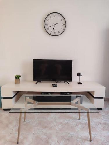 a white table with a tv and a clock on a wall at Apartment by the beach truman 8-1 in Qiryat H̱ayyim