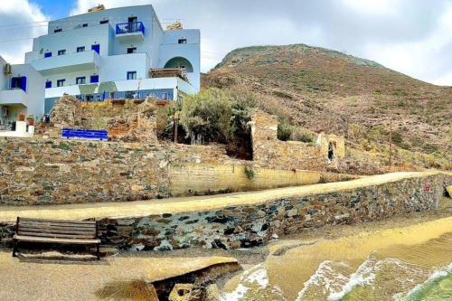 a building sitting on top of a stone wall next to a bench at Eleni On The Beach in Katapola