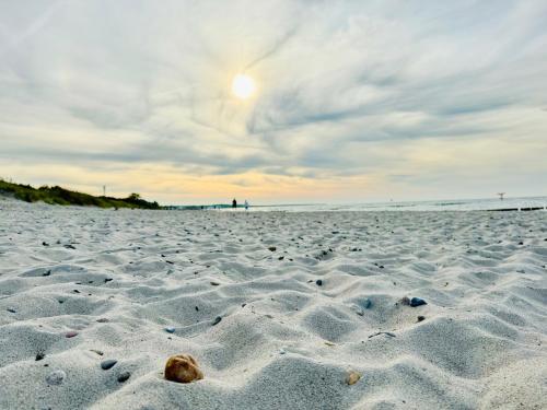 a sandy beach with the sun setting in the background at Pension Ostsee-Strand in Börgerende-Rethwisch