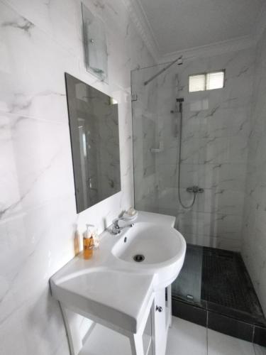 un bagno bianco con lavandino e doccia di Kaeya a Flic-en-Flac