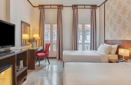 a hotel room with two beds and a flat screen tv at Village Hotel Albert Court by Far East Hospitality in Singapore