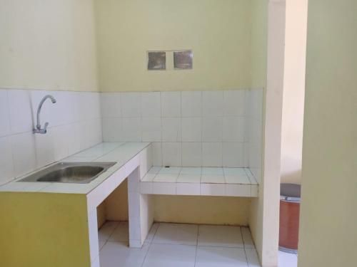a white kitchen with a sink and a counter at Aqilakost Gadog Puncak Bogor in Bogor
