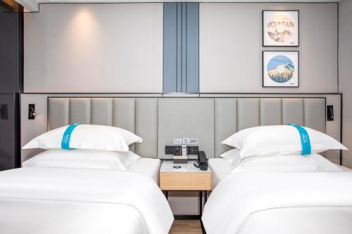 two beds sitting next to each other in a room at VX Hotel Shanghai Yixian Road Dabaishu in Shanghai