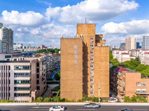a tall brick building in the middle of a city at VX Hotel Shanghai Yixian Road Dabaishu in Shanghai