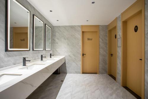 a bathroom with a row of sinks and mirrors at VX Hotel Shanghai Yixian Road Dabaishu in Shanghai
