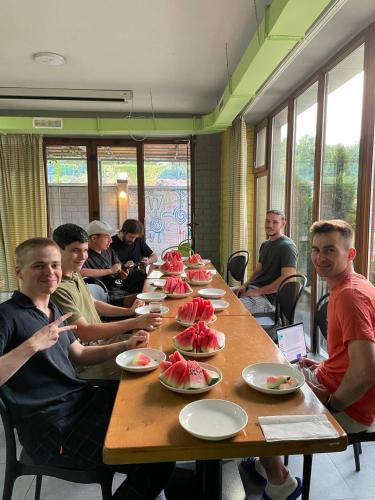 a group of people sitting at a long table with food at ololoFreelander Hostel&Coworking in Bishkek