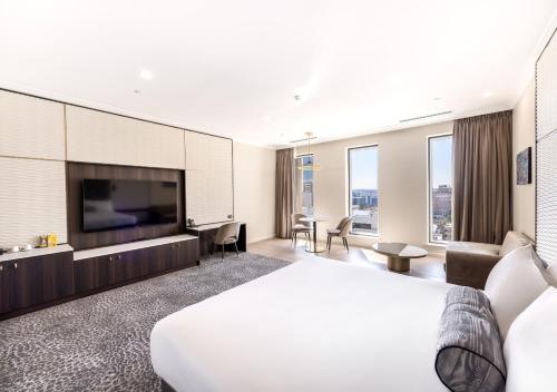 a hotel room with a bed and a flat screen tv at Duxton Hotel Perth in Perth