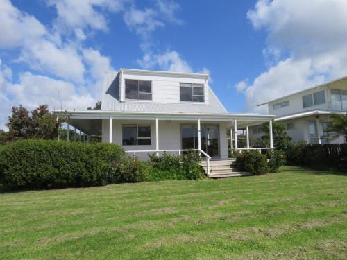 a white house with a lawn in front of it at Raines Retreat - Taipa Beach Bach in Taipa