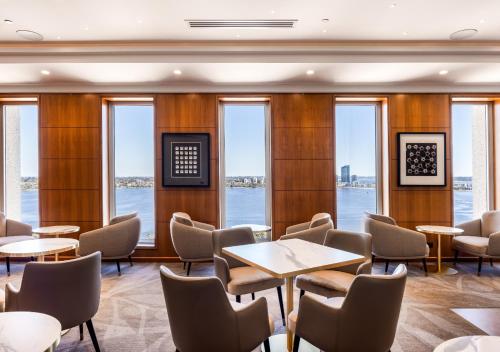 a restaurant with tables and chairs and windows at Duxton Hotel Perth in Perth