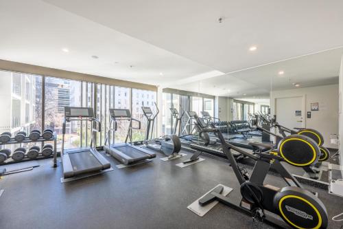 a gym with rows of treadmills and cardio machines at Central located 2 bedroom Apartment in Canberra with Parking in Canberra