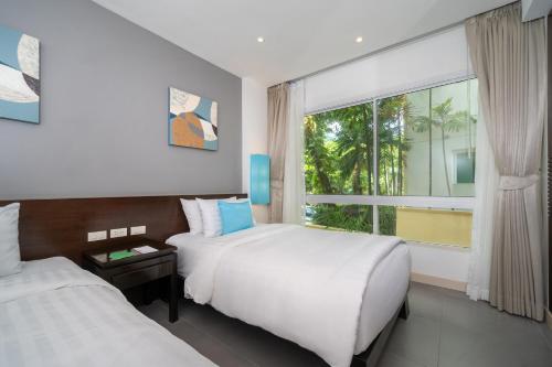 a hotel room with two beds and a window at Karon Beachfront Apartment 703 in Karon Beach