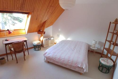une chambre avec un lit, un bureau et une fenêtre dans l'établissement Villa 10p, exposition sud, la plage de sable au bout du jardin, à Saint-Briac-sur-Mer