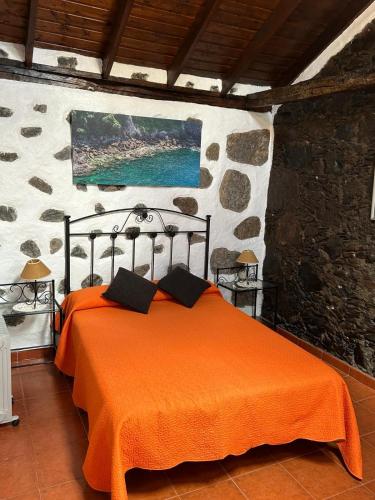 a bedroom with a bed with an orange blanket at Casa Rural La Vega in Agulo