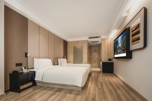 a bedroom with a white bed and a flat screen tv at Atour Hotel -Du Fu Thatched Cottage in Chengdu