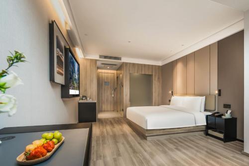 a hotel room with a bed and a bowl of fruit at Atour Hotel -Du Fu Thatched Cottage in Chengdu