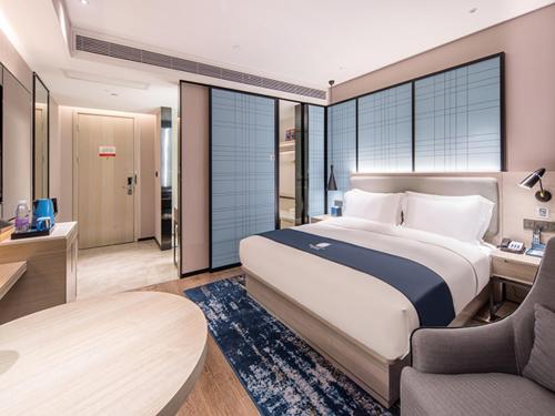 a bedroom with a bed and a desk and a chair at Echarm Hotel Nanning Jinhu Square Metro Station Branch in Nanning