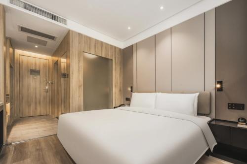 a bedroom with a large white bed and wooden walls at Atour Hotel -Du Fu Thatched Cottage in Chengdu