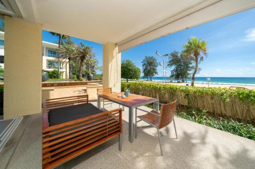 a patio with a table and chairs and the beach at Karon Beachfront Apartment 703 in Karon Beach