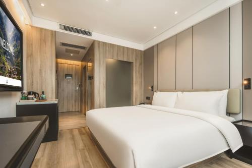 a bedroom with a large white bed and a television at Atour Hotel -Du Fu Thatched Cottage in Chengdu