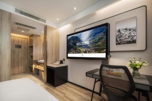 a hotel room with a television on the wall at Atour Hotel -Du Fu Thatched Cottage in Chengdu