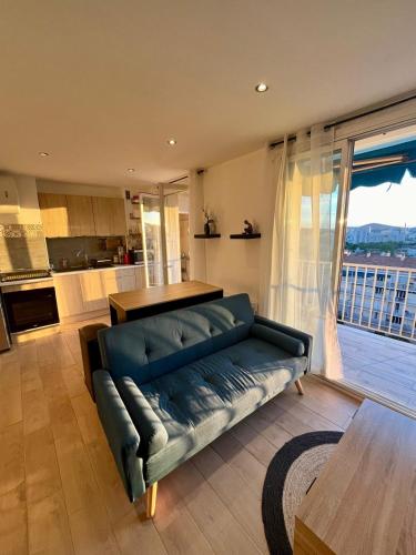 un salon avec un canapé bleu et une cuisine dans l'établissement Appartement spacieux 3 chambre, à Toulon