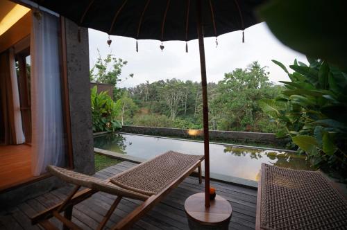 a patio with a table and chairs and an umbrella at The Shanti Graha Villas in Ubud