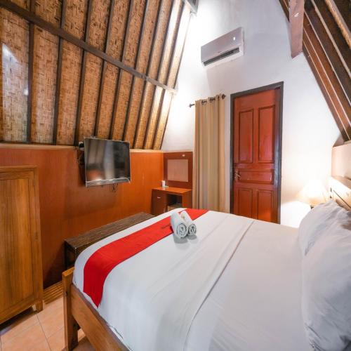 a bedroom with a bed and a tv on a wall at RedDoorz at Ocean 2 Gili Trawangan in Gili Trawangan