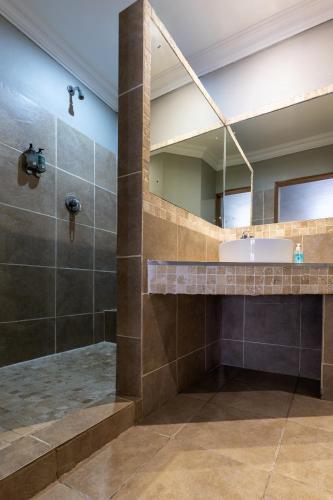 a bathroom with a shower and a sink and a mirror at Solo Gracia Guesthouse in Bloemfontein