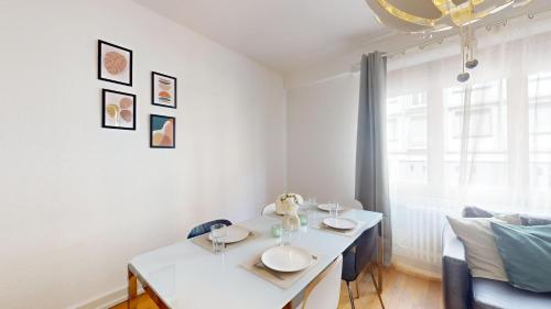 une salle à manger blanche avec une table et un canapé dans l'établissement La Symphonie de l'Orangerie, à Strasbourg