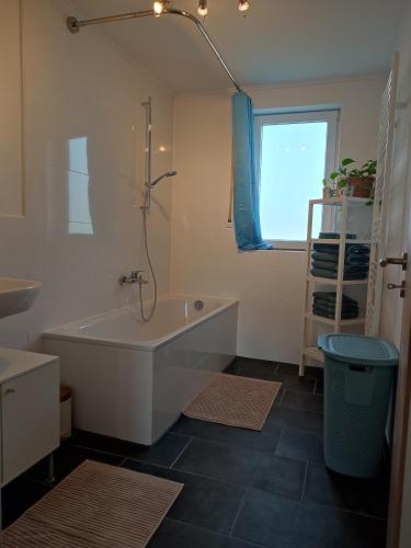 a white bathroom with a tub and a window at Ferienwohnung Weitblick in Dachau