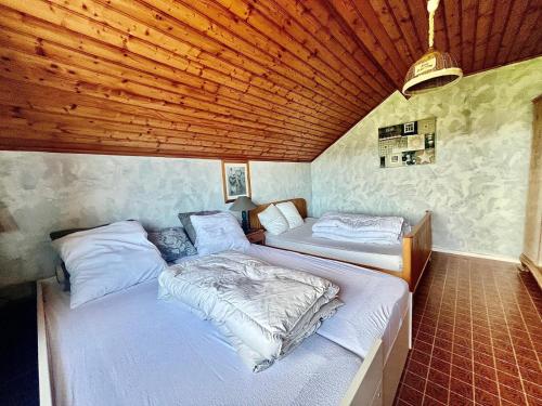 two beds in a room with wooden ceilings at Le Nid du Lac in Saint-Point-Lac