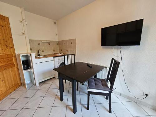une cuisine avec une table et une télévision murale dans l'établissement Pleins soleils 104, à Lamalou-les-Bains
