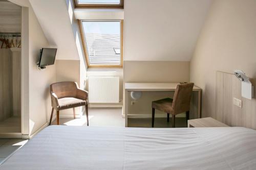 a bedroom with a bed and two chairs and a desk at La Couronne in Welkenraedt