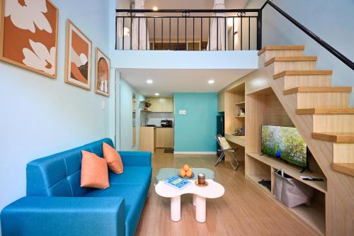 胡志明市Jade Garden by La Doma Express的客厅里有一张蓝色的沙发和一座楼梯