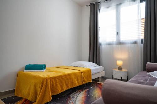 a bedroom with a bed with a yellow blanket on it at Ecumes Sauvages - DODOTERLA in Manapany-les Bains