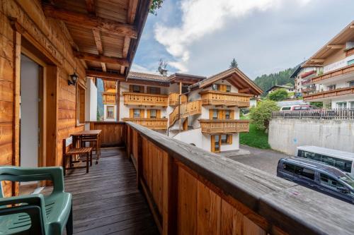 a balcony with a wooden railing with a table and chairs at Cesa Rosy in Campitello di Fassa