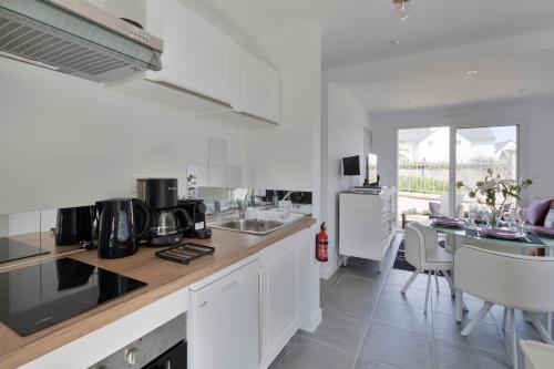 une cuisine avec des placards blancs et une salle à manger avec une table dans l'établissement La Garde & Le Repos - Proche plage St Lunaire, à Saint-Lunaire