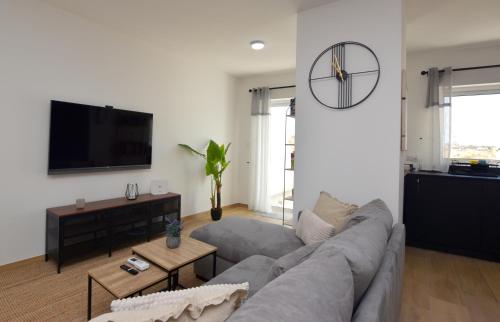 a living room with a gray couch and a flat screen tv at Spacious 3BR Penthouse with Large Front Terrace - Stone BBQ & Sun Loungers in Taʼ Bullara