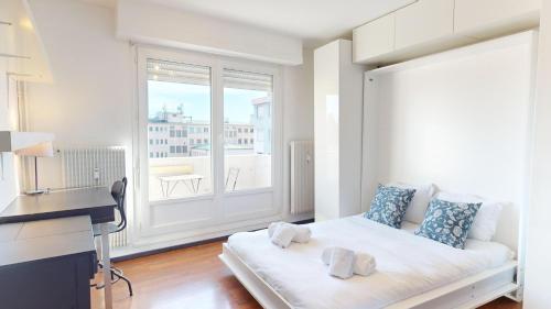 Cette chambre blanche comprend un lit et un bureau. dans l'établissement Meublé du Faubourg - Centre/Gare, à Strasbourg