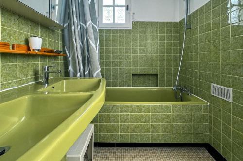 a green bathroom with a tub and a sink at Bug Ar Mor - Vue Exceptionnelle des 7 Îles in Penvénan