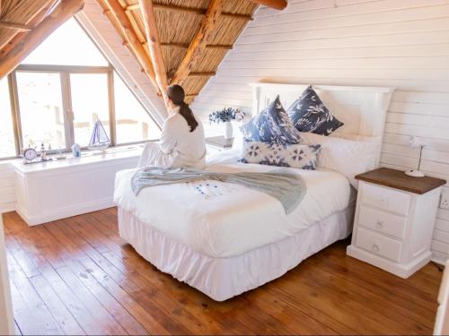 a woman sitting on a bed in a room with a window at Chicuanga in Chizavane