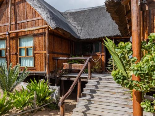 a house with a wooden porch and stairs to it at Chicuanga in Chizavane