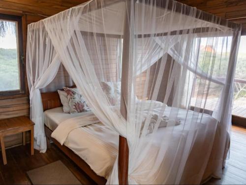 a bedroom with a canopy bed with white curtains at Chicuanga in Chizavane