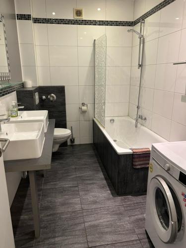 a bathroom with a sink and a tub and a washing machine at Apartment Breite Str. 83 in Witten