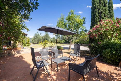 a group of chairs and a table with an umbrella at Villa Lola by VacaVilla in Nebbiano